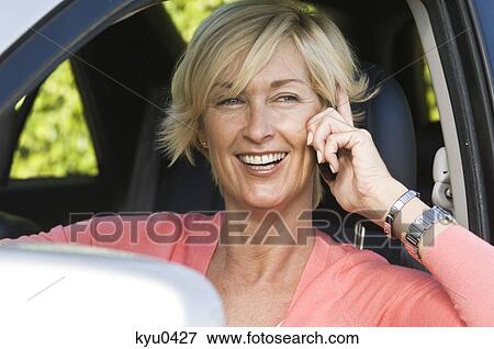 Stock Photo - Woman in a car and talking on a mobile phone. Fotosearch