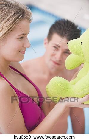 Woman playing with a teddy bear and a man looking at her View Large Photo Image Stock Photo - Woman playing with a teddy bear and a man looking at her. Fotosearch