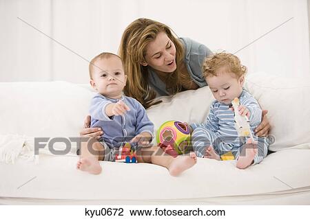 Stock Image - Woman playing with her son and daughter on a couch. Fotosearch