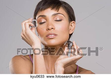 Woman rubbing ice cubes on her face View Large Photo Image Stock Image - Woman rubbing ice cubes on her face. Fotosearch