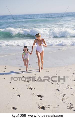 Woman running on the beach with her daughter View Large Photo Image Stock Photograph - Woman running on the beach with her daughter. Fotosearch