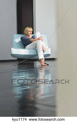 Picture - Woman sitting on a couch. Fotosearch