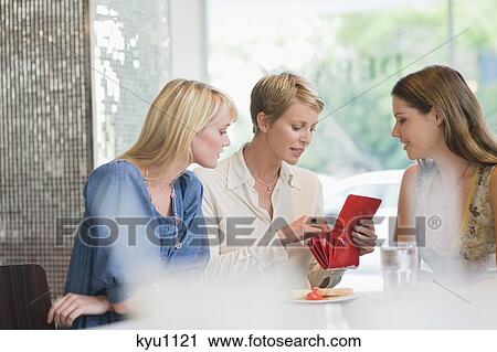 Woman sitting with her friends in a restaurant and looking into her wallet View Large Photo Image Stock Image - Woman sitting with her friends in a restaurant and looking into her wallet. Fotosearch