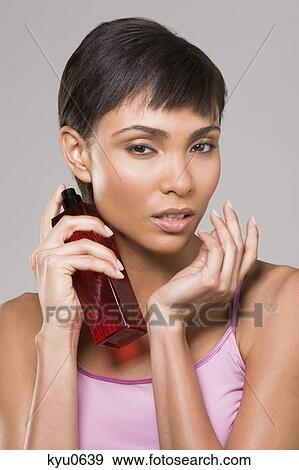 Stock Photo - Woman spraying perfume on her neck. Fotosearch