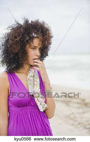 Stock Photograph - Woman standing on the beach and looking surprised. Fotosearch