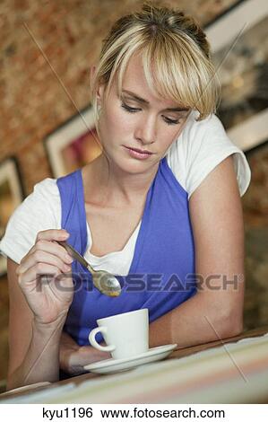 Stock Photograph - Woman stirring coffee in a cafe. Fotosearch