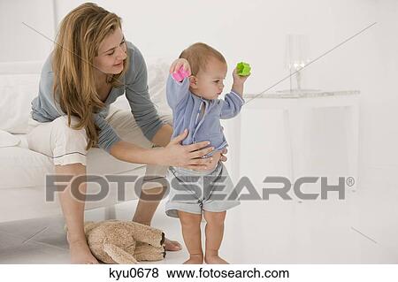 Stock Photo - Woman supporting her daughter learning to walk. Fotosearch