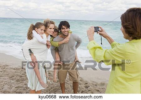 Stock Photo - Woman taking a picture of her family with a digital camera. Fotosearch