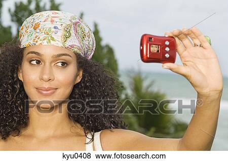 Stock Photo - Woman taking a picture of herself with a digital camera. Fotosearch