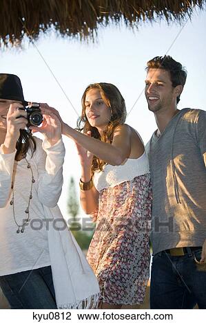 Woman taking a picture with her friends standing beside her View Large Photo Image Stock Image - Woman taking a picture with her friends standing beside her. Fotosearch