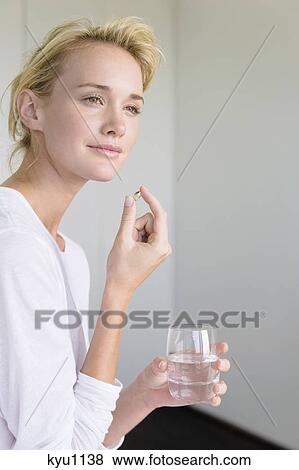 Stock Photo - Woman taking an Omega-3 capsule. Fotosearch