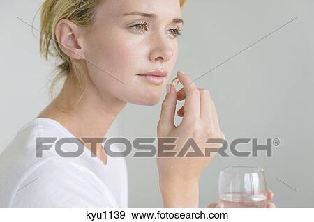 Stock Photo - Woman taking an Omega-3 capsule. Fotosearch