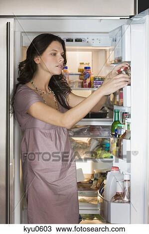 Stock Image - Woman taking out a bottle from a refrigerator. Fotosearch