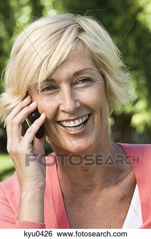 Woman talking on a mobile phone and smiling View Large Photo Image Stock Photograph - Woman talking on a mobile phone and smiling. Fotosearch