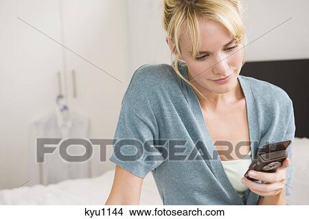 Woman text messaging on a mobile phone View Large Photo Image Picture - Woman text messaging on a mobile phone. Fotosearch