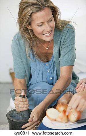 Woman using mortar and pestle with a person chopping onions View Large Photo Image Stock Image - Woman using mortar and pestle with a person chopping onions. Fotosearch