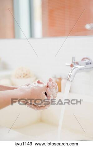 Stock Photo - Woman washing hands in the bathroom. Fotosearch