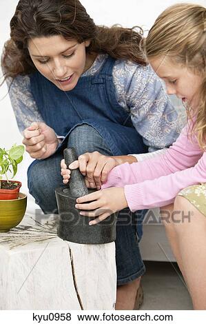 Stock Photo - Women and her daughter with a mortar and pestle. Fotosearch