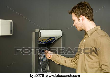Stock Photo - Young man using an ATM. Fotosearch