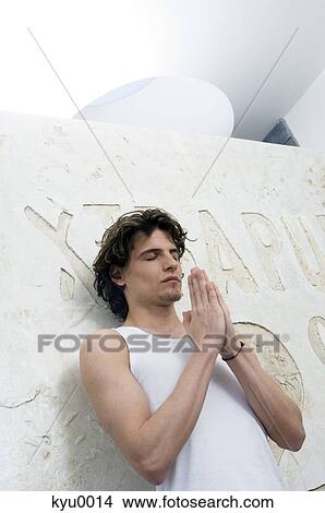 Young man with folded hands, closed eyes View Large Photo Image Picture - Young man with folded hands, closed eyes. Fotosearch