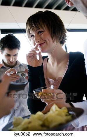 Young smiling woman holding glass of champagne, man with digital camera in background View Large Photo Image Stock Image - Young smiling woman holding glass of champagne, man with digital camera in background. Fotosearch