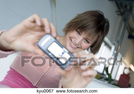 Young smiling woman taking picture with camera phone View Large Photo Image Stock Photo - Young smiling woman taking picture with camera phone. Fotosearch