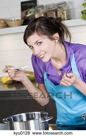 Stock Photo - Young smiling woman tasting food. Fotosearch