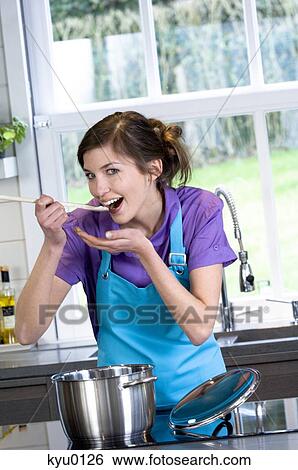 Stock Photograph - Young smiling woman tasting food. Fotosearch
