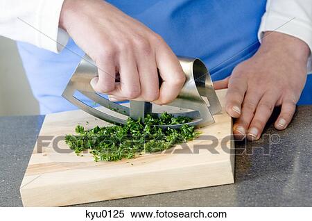 Stock Photography - Young woman chopping parsley, close-up. Fotosearch