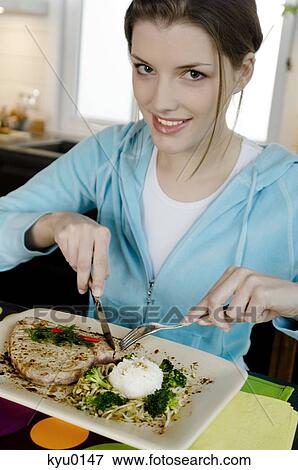 Young woman eating meat and rice View Large Photo Image Stock Photo - Young woman eating meat and rice. Fotosearch