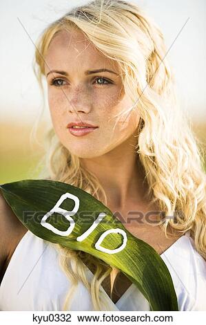 Stock Image - Young woman holding a leaf with "BIO" lettering. Fotosearch