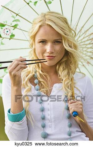 Young woman holding chopsticks and umbrella View Large Photo Image Stock Photography - Young woman holding chopsticks and umbrella. Fotosearch