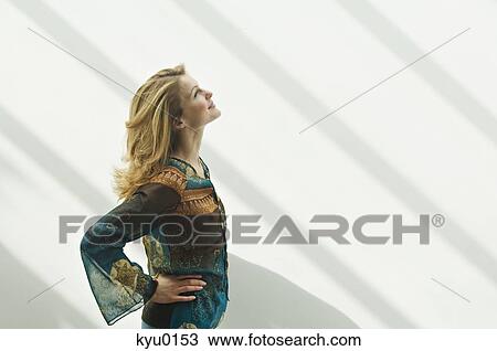 Young woman in profile looking up, arms akimbo View Large Photo Image Stock Image - Young woman in profile looking up, arms akimbo. Fotosearch