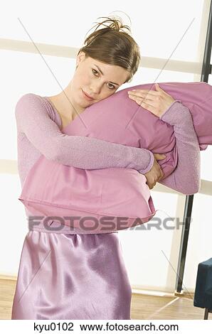 Young woman looking at camera, holding tight a pillow View Large Photo Image Stock Image - Young woman looking at camera, holding tight a pillow. Fotosearch