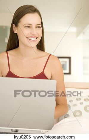 Young woman smiling using a laptop View Large Photo Image Stock Photography - Young woman smiling using a laptop. Fotosearch