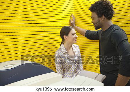 Stock Photography - Business executives standing near photocopy machine and smiling. Fotosearch