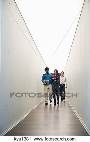 Business executives walking in the corridor of an office View Large Photo Image Stock Image - Business executives walking in the corridor of an office. Fotosearch