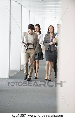 Business executives walking in the corridor of an office View Large Photo Image Stock Photo - Business executives walking in the corridor of an office. Fotosearch