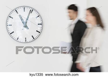 Business executives walking together in front of a wall clock View Large Photo Image Stock Photography - Business executives walking together in front of a wall clock. Fotosearch