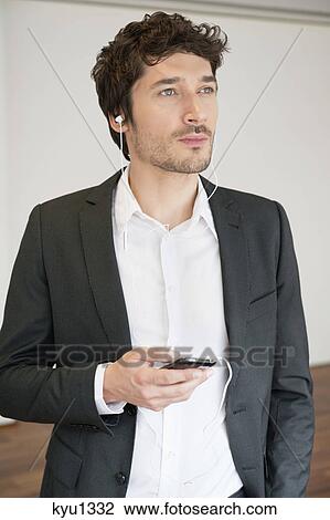 Businessman listening to music with a mobile phone View Large Photo Image Stock Image - Businessman listening to music with a mobile phone. Fotosearch
