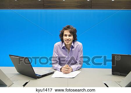 Businessman smiling with a laptop in a conference room View Large Photo Image Stock Photo - Businessman smiling with a laptop in a conference room. Fotosearch