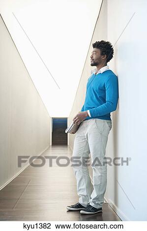 Businessman standing in the corridor of an office View Large Photo Image Stock Image - Businessman standing in the corridor of an office. Fotosearch