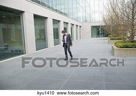 Stock Image - Businessman text messaging on a mobile phone. Fotosearch