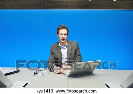 Businessman working on a laptop in a conference room View Large Photo Image Stock Photo - Businessman working on a laptop in a conference room. Fotosearch