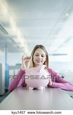 Businesswoman inserting a coin into a piggy bank View Large Photo Image Stock Photo - Businesswoman inserting a coin into a piggy bank. Fotosearch