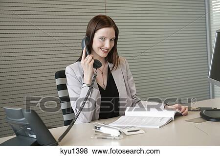 Stock Photo - Businesswoman talking on a telephone in an office. Fotosearch