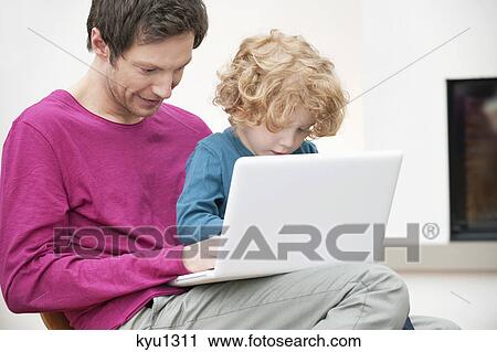 Close-up of a man assisting his son in using a laptop View Large Photo Image Stock Image - Close-up of a man assisting his son in using a laptop. Fotosearch