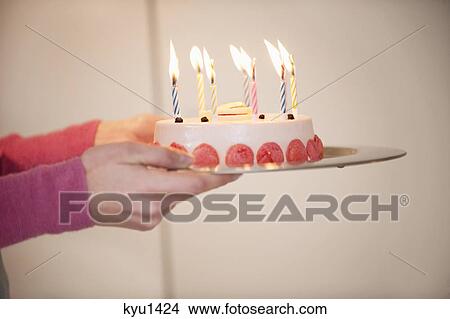 Picture - Close-up of a woman's hands holding a birthday cake. Fotosearch