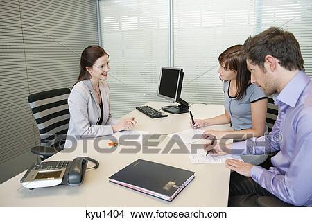 Couple signing agreement form in a real estate agent's office View Large Photo Image Picture - Couple signing agreement form in a real estate agent's office. Fotosearch