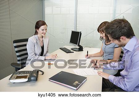 Couple signing agreement form in a real estate agent's office View Large Photo Image Stock Photography - Couple signing agreement form in a real estate agent's office. Fotosearch